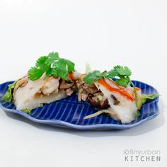 a blue plate topped with meat and veggies on top of a white table