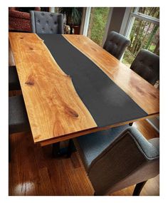 a wooden table with chairs around it and a black mat on the top that is in front of a window