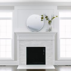 a living room with a fire place, mirror and vase on the mantel above it