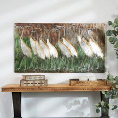 a group of white birds standing on top of a wooden table next to a potted plant