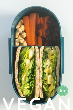 an open lunch box with two sandwiches, carrots and raisins