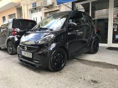 two smart cars parked in front of a store