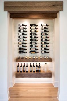 wine bottles are lined up on the wall in front of an open shelf that holds several bottles