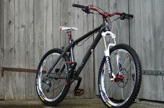 a black and white bike leaning against a wooden fence