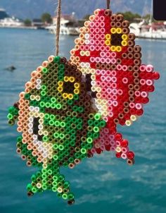 an ornament made out of legos is hanging from a rope near the water