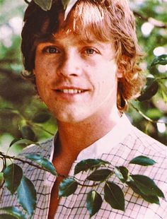 a young man is posing for a photo with leaves on his head and shirt over his shoulders