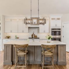 a large kitchen with an island in the middle and three stools at the end