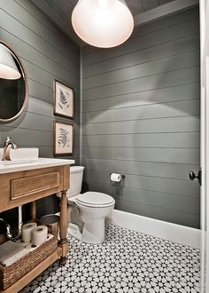 a white toilet sitting next to a sink in a bathroom under a round light fixture