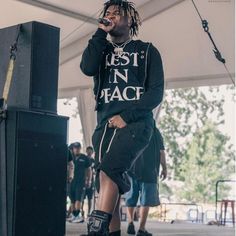 a young man standing on top of a stage with his feet in the air while singing into a microphone