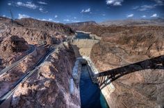 an aerial view of a bridge over a river in the middle of a mountain range