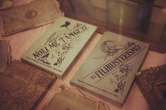 three books sitting on top of a table next to an open box with writing on it