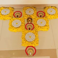 a cross made out of yellow and red flowers with bells on the floor next to it