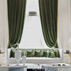 a living room filled with white furniture and green curtains