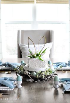 a table topped with a cake covered in white frosting and an air plant sitting on top of it