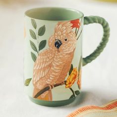 a coffee mug with an image of a parrot on it's front and side