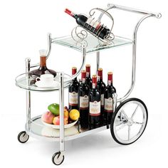 a wine cart filled with lots of bottles next to a bowl of fruit and vegetables