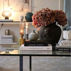 a table topped with books and a vase filled with flowers next to a lit candle