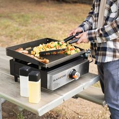 a man is grilling food on an outdoor table