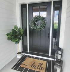 a black front door with a welcome mat and a potted plant on the porch