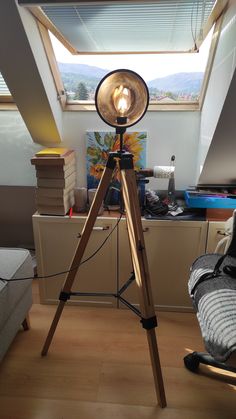 a tripod light sitting on top of a wooden floor in front of a window