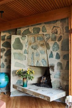 a stone fireplace in a room with wood flooring and walls made out of stones