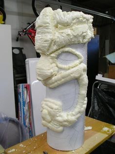 a large white sculpture sitting on top of a wooden table next to a refrigerator freezer