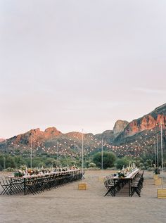 a table set up on the beach with mountains in the backgroung area