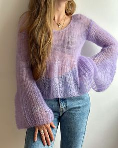 a woman wearing a purple sweater and jeans