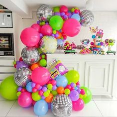 a bunch of balloons that are on the ground in front of a kitchen counter top