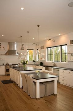 a large kitchen with white cabinets and black counter tops is pictured in this image, the island has four stools on it