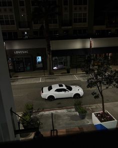 a white car parked on the side of a street at night in front of a building