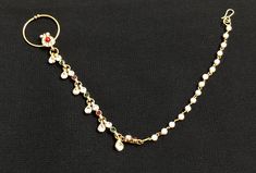 a gold chain with white and red stones on it, attached to a black background