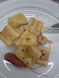 a white plate topped with ravioli and shrimp