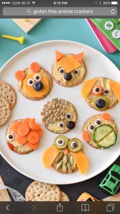 a white plate topped with crackers covered in animal faces and veggie eyes