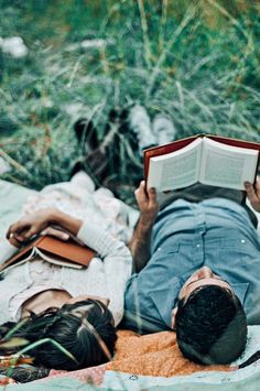 a man laying on the ground reading a book