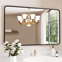 a bathroom sink with a mirror and flowers in the vase next to it on the counter