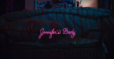 a neon sign that reads, jenny's body on the back of a couch