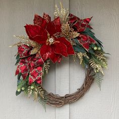 a christmas wreath with poinsettis and greenery hanging on a door