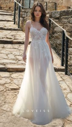 a woman in a white dress walking down a stone walkway with an open back and long train