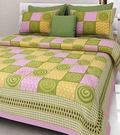 a bed with green and pink bedspread, pillows and pillow cases on it