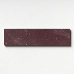 a piece of red marble sitting on top of a white surface