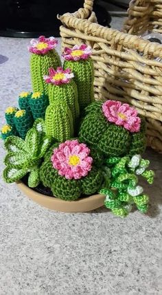 small crocheted cactus plants in a bowl on the floor next to a wicker basket