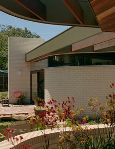 the outside of a house with flowers in front of it and a patio area next to it