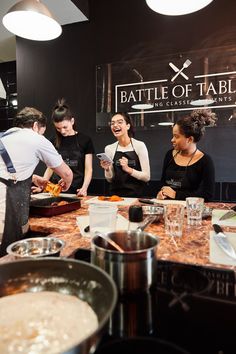 a group of people standing around a table with food