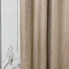 the curtain is closed in front of an ornate white paneled wall and window frame