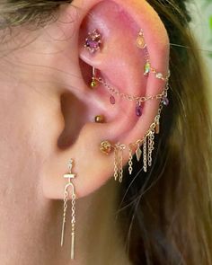 a close up of a person wearing ear piercings with chains and beads on them