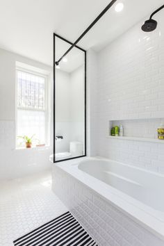 an image of a white bathroom with black and white tiles on the floor, along with a large bathtub