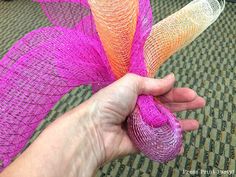 a hand holding a piece of pink and orange mesh