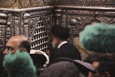 a group of men standing next to each other in front of a metal structure with carvings on it