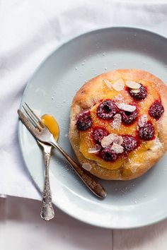 a pastry with berries and almonds is on a white plate next to a fork